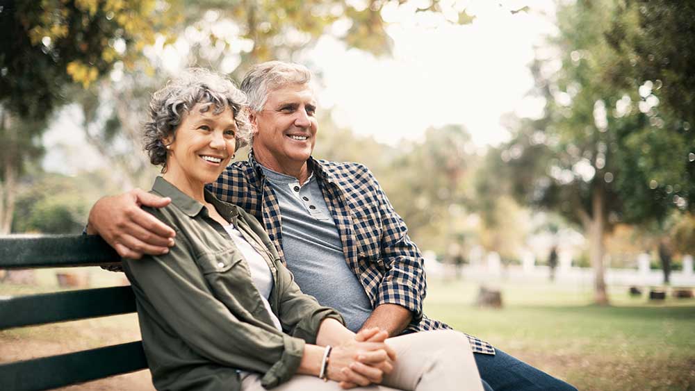 para siedzi na ławce i kładzie rękę na jej ramieniu
