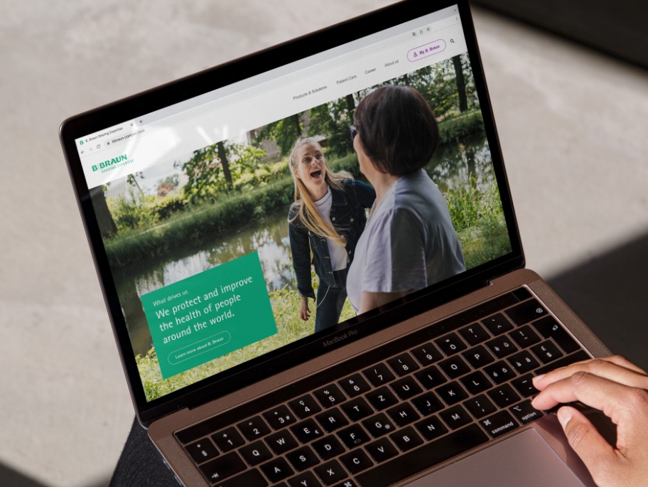 Un laptop con il sito web di B. Braun aperto e una mano appoggiata in basso a destra del laptop. 