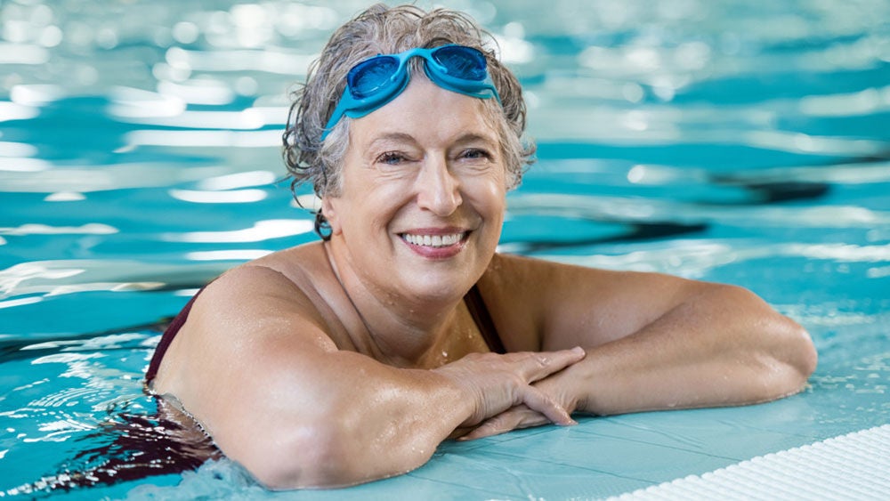 femme dans une piscine portant des lunettes de natation sur le front