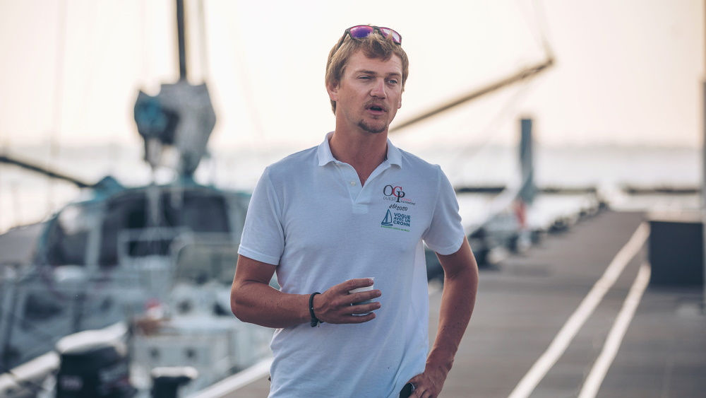 Ein Mann spricht mit einer Yacht im Hintergrund