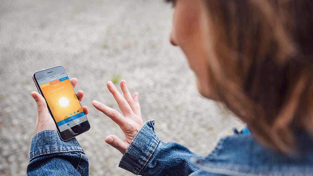 Ung kvinde med HC&ME-hydrocephalusdagbogsappen på sin smartphone