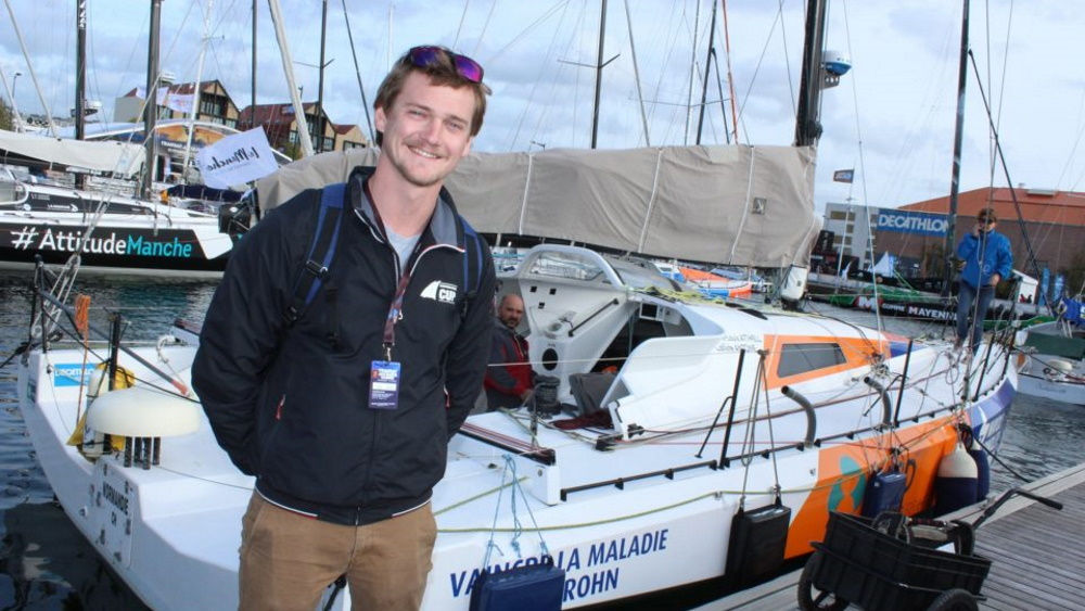 Homme souriant dans le port devant un yacht