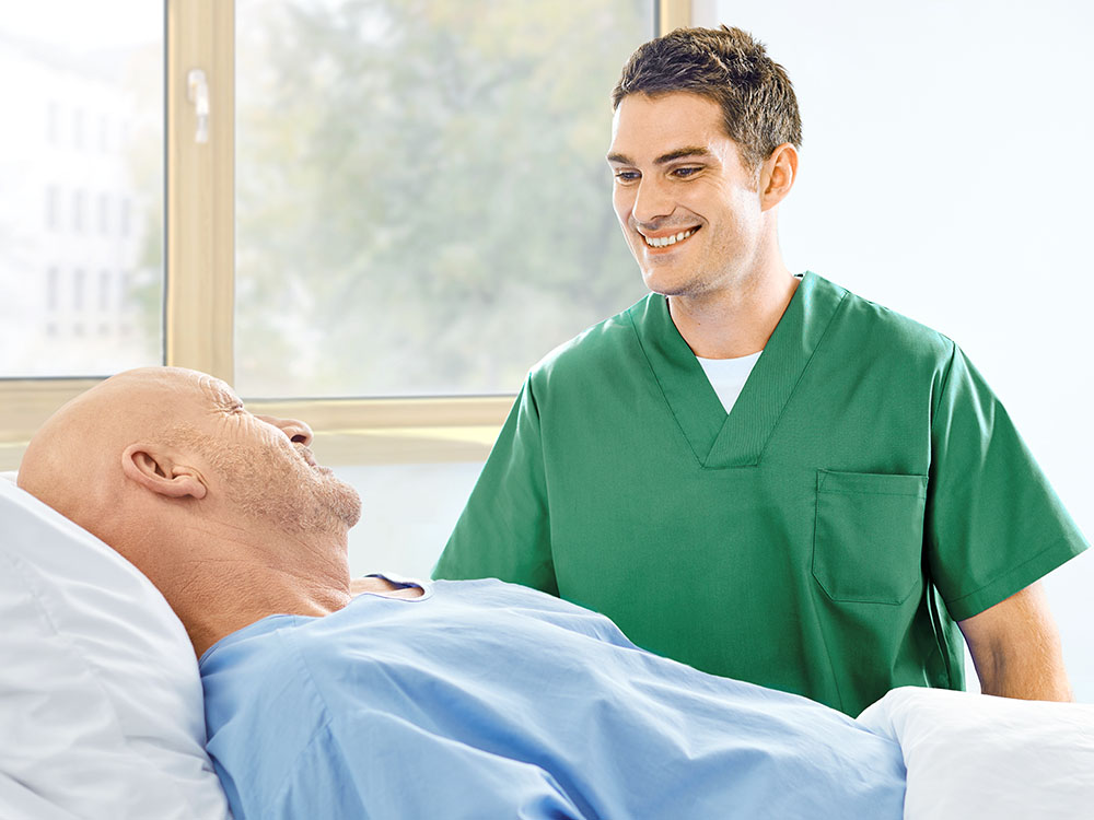 Pflegekraft und Patient sprechen am Bett