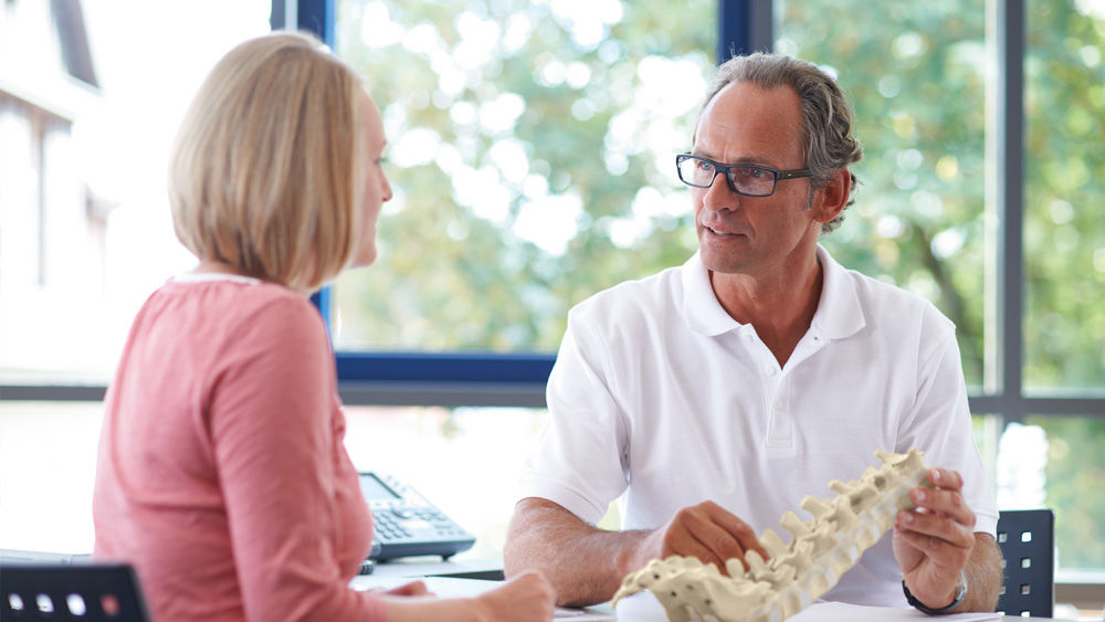 Lekarz omawia z pacjentem minimalnie inwazyjną chirurgię krążka międzykręgowego