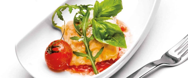 Weißer Teller mit einem Gericht mit Tomate, Ei und Gemüse