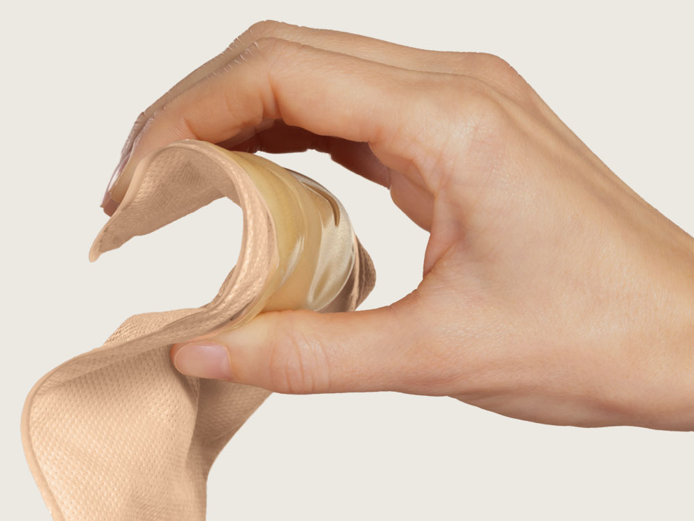 a hand bends the stoma bag