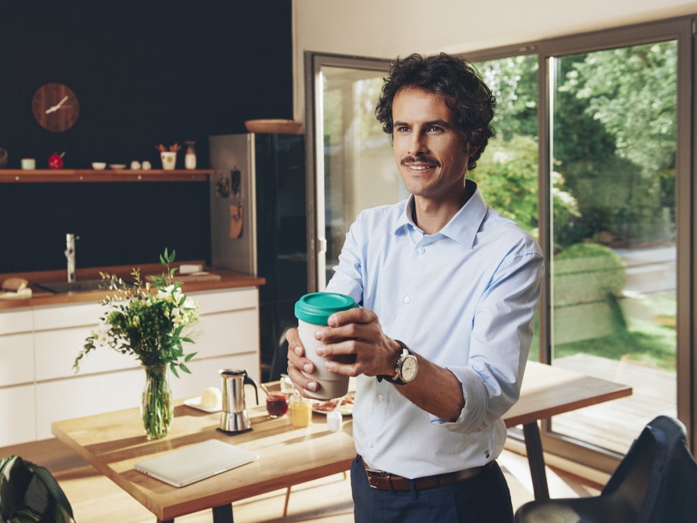 Homme debout dans une maison privée tenant une tasse de café