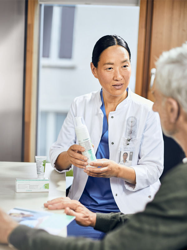 Female doctor shows prontoderm foam to an eldery patient