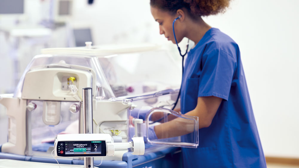 Een verpleegkundige verzorgt een pediatrische patiënt met een B. Braun smart infusieapparaat in de buurt.