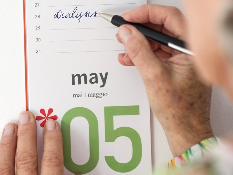 Een hand schrijft dialyse in een kalender voor 28 mei met een balpen