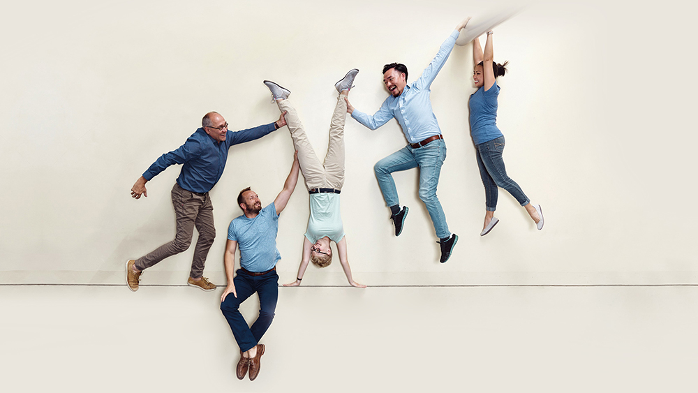 Jedna osoba odwrócona do góry nogami, a trzy inne osoby trzymają je