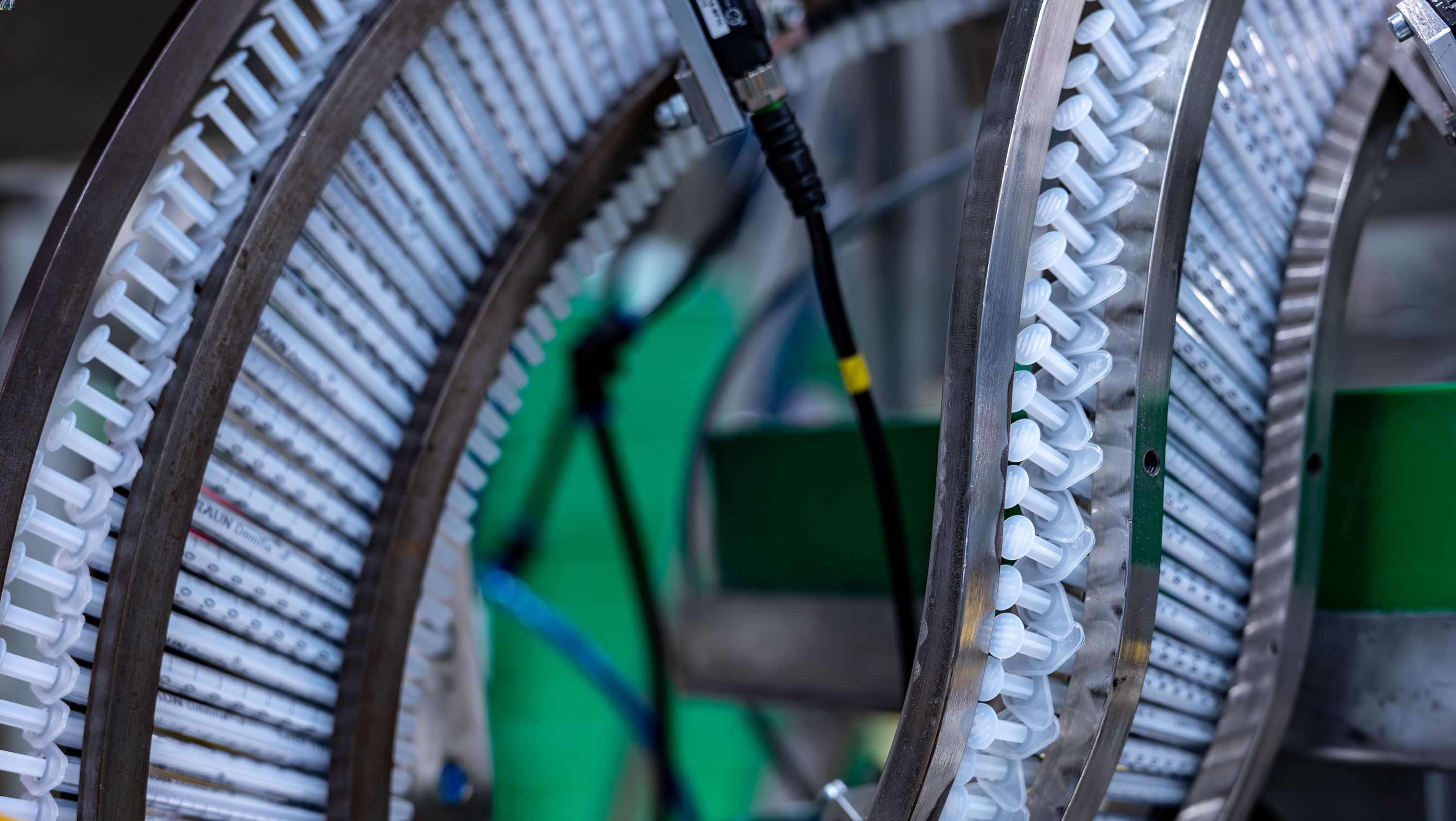 Muitas seringas em linha num ambiente de produção. Simboliza a nossa análise do ciclo de vida do produto para determinar o impacto ambiental total de um produto, desde o fornecimento das matérias-primas até à eliminação. 