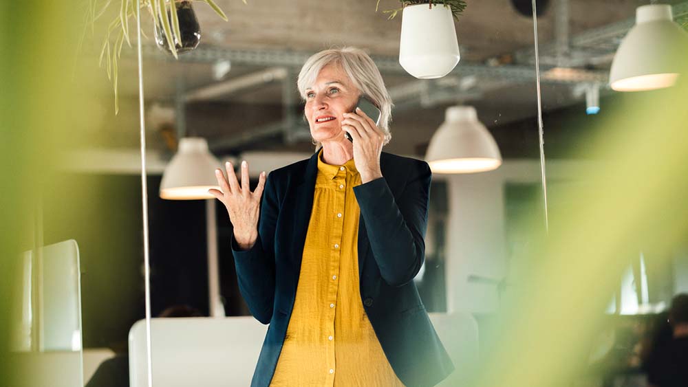 An elderly person having a business call in the office